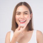 smiling woman holding invisalign braces