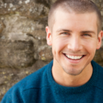 Attractive young man sitting, smiling outside