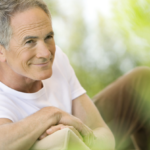 Happy middle aged man reclining on deck chair in garden