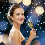 smiling woman in evening dress with glass of sparkling wine