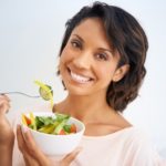 Portrait of a young woman enjoying a salad at home.