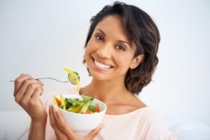 Portrait of a young woman enjoying a salad at home.