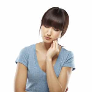 Japanese woman suffering from toothache holding a hand on jaw