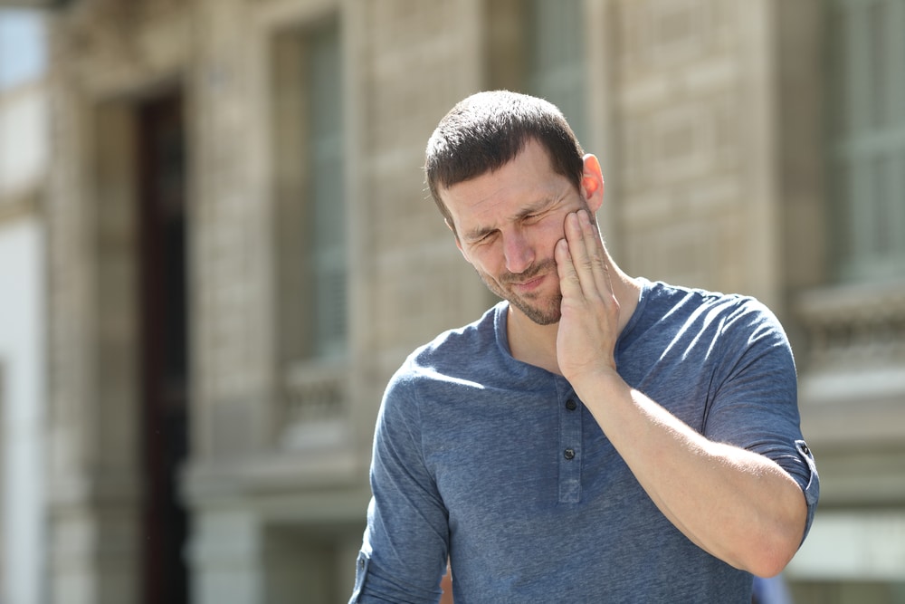 Stressed man suffering tooth ache in the street