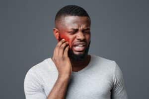 Sad man touching his cheek in discomfort, symbolizing gum problems and periodontal disease